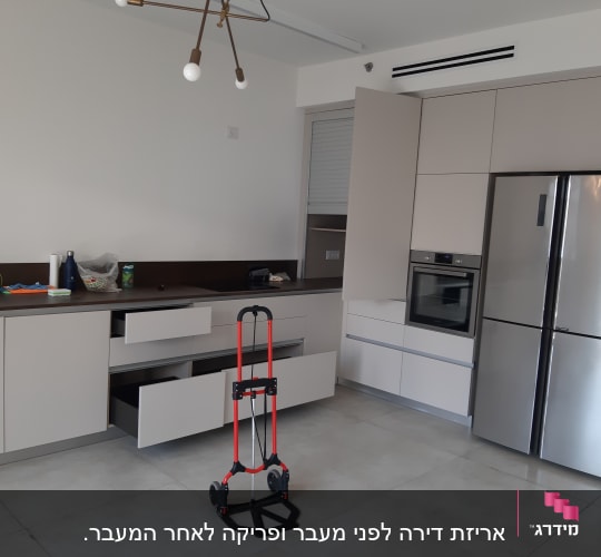 מטבח עם ארונות פתוחים ועגלת משא על הרצפה